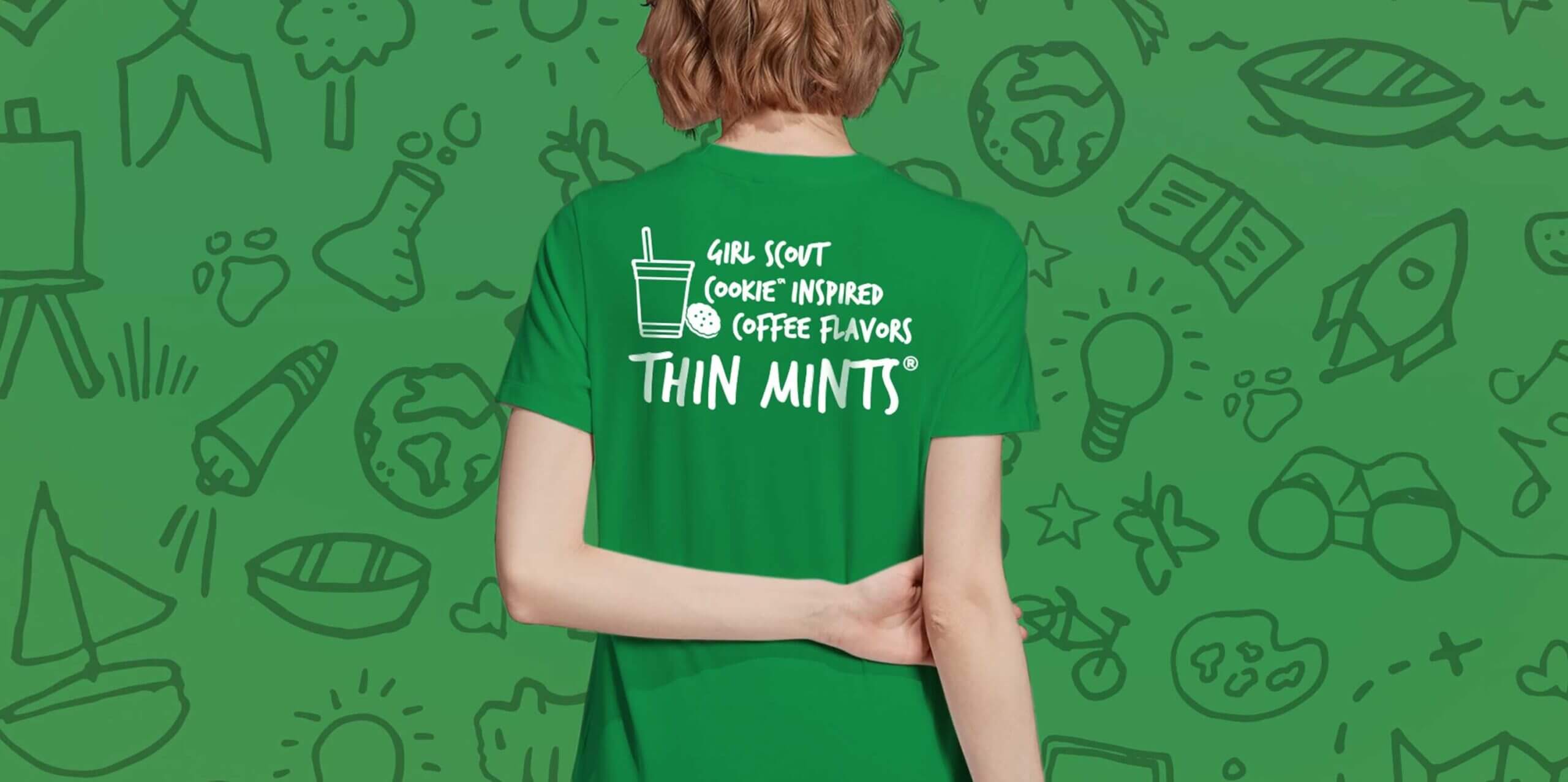 A person in a green Dunkin' Donuts tshirt that reads "Girl Scout Cookie Inspired Coffee Flavors Thin Mints"