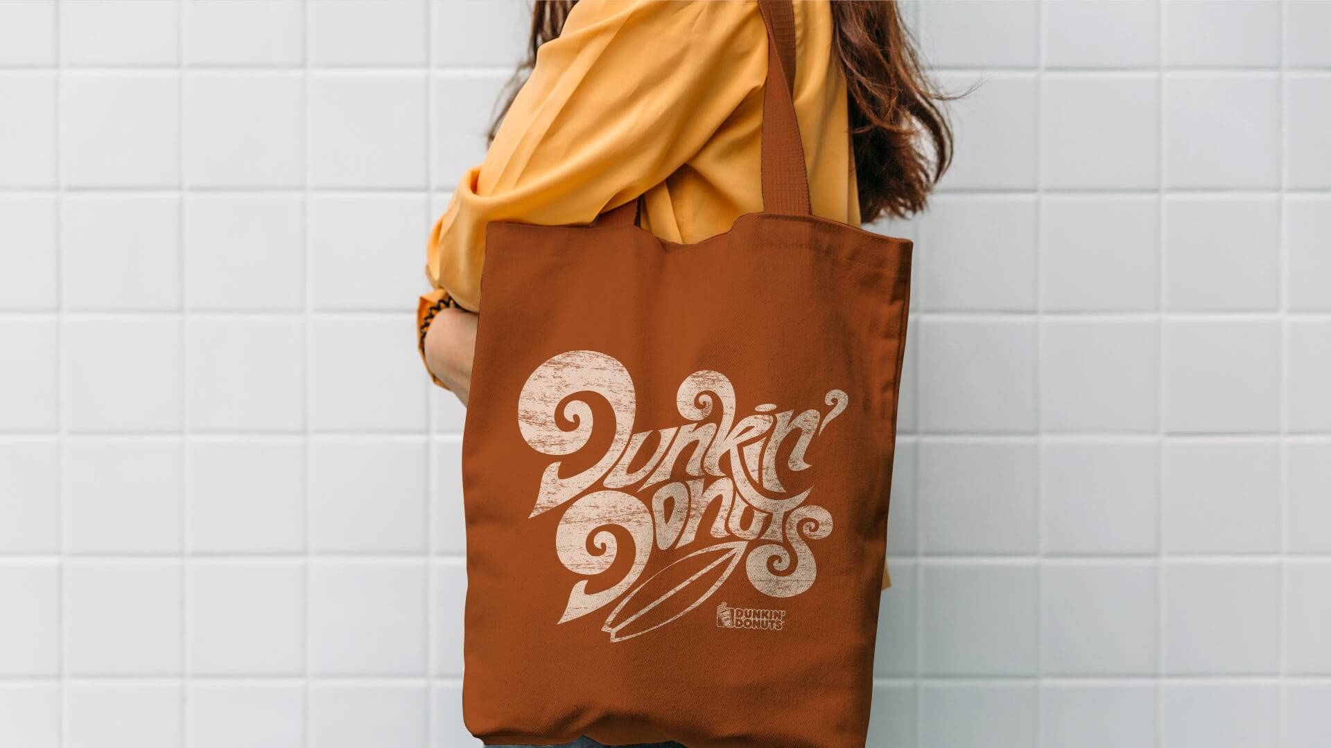 A person with a Dunkin' Donuts canvas bag over their sholder